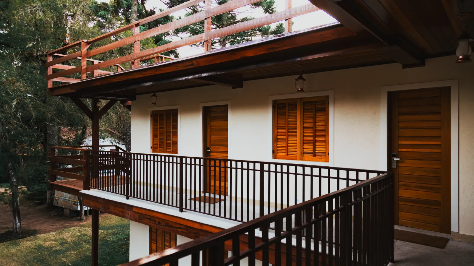 Guest rooms with wooden doors along a shaded balcony